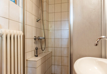 Lille brusekabine med hvide fliser, håndvask og radiator i kabinen Niederaula, Tyskland.