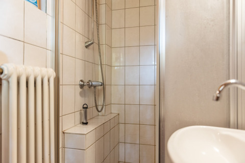 Lille brusekabine med hvide fliser, håndvask og radiator i kabinen Niederaula, Tyskland.