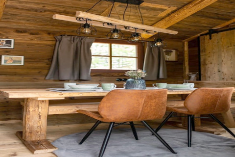Coin repas chaleureux dans une tiny house en Allemagne, avec table en bois, chaises brunes et déco rustique.