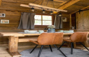 Zona pranzo accogliente in una tiny house in Germania con tavolo in legno, sedie marroni e atmosfera rustica.