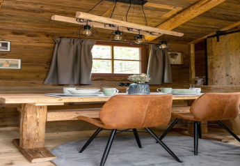 Zona pranzo accogliente in una tiny house in Germania con tavolo in legno, sedie marroni e atmosfera rustica.