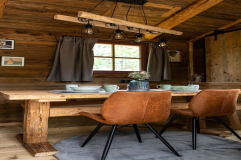 Acogedor comedor en tiny house en Alemania con mesa de madera, sillas marrones y paredes rústicas.