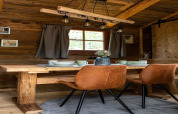 Coin repas chaleureux dans une tiny house en Allemagne, avec table en bois, chaises brunes et déco rustique.