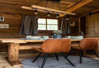 Coin repas chaleureux dans une tiny house en Allemagne, avec table en bois, chaises brunes et déco rustique.