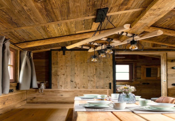 Interno in legno di una tiny house con tavola apparecchiata e lampada rustica in Germania.