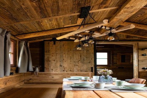 Interior de casa pequeña de madera con mesa puesta y lámpara rústica en Tiny House, Alemania.