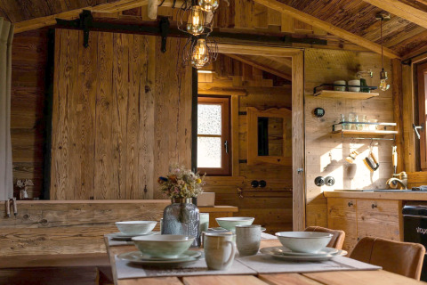 Intérieur d'une tiny house en Allemagne, table en bois, décor chaleureux et cuisine rustique en bois.