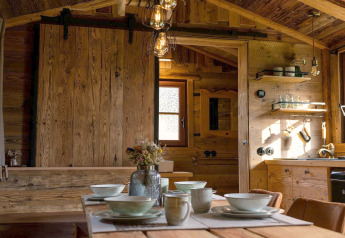 Interno di una tiny house in Germania, con tavolo in legno, decorazioni accoglienti e cucina rustica.