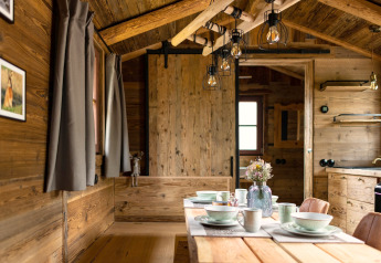 Interno di una tiny house in legno in Germania, tavolo da pranzo e atmosfera accogliente e rustica.