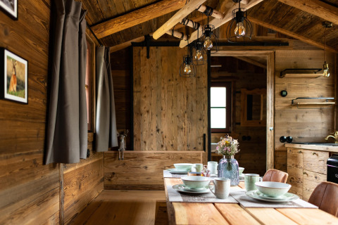 Interior de una tiny house de madera en Alemania, mesa de comedor y ambiente acogedor y rústico.
