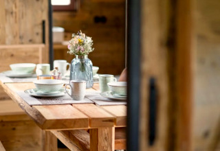 Table en bois dressée avec vaisselle en céramique et vase de fleurs dans un tiny house en Allemagne.