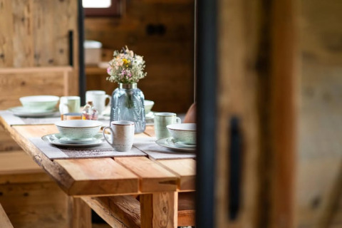 Mesa de madera con vajilla de cerámica y un jarrón de flores silvestres en una tiny house en Alemania.