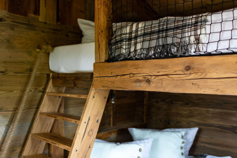 Litera de madera con escalera y almohadas en una tiny house en Alemania, decoración rústica y acogedora.