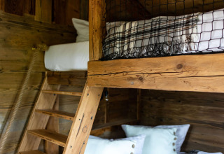 Litera de madera con escalera y almohadas en una tiny house en Alemania, decoración rústica y acogedora.