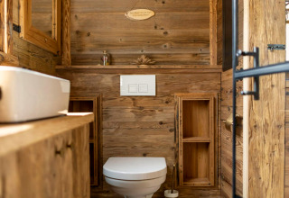 Salle de bain moderne en bois dans une tiny house en Allemagne, avec WC, lavabo et lumière naturelle.