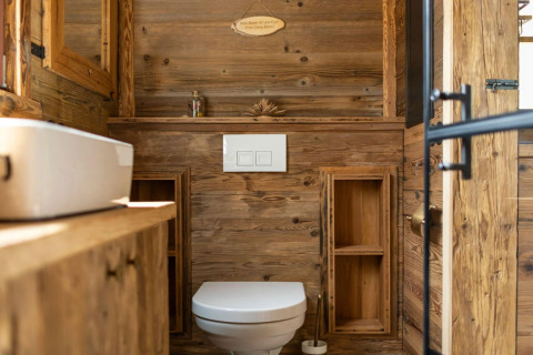 Moderno baño de madera en una tiny house en Alemania, con inodoro, lavabo y luz natural.