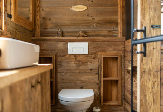Moderno baño de madera en una tiny house en Alemania, con inodoro, lavabo y luz natural.