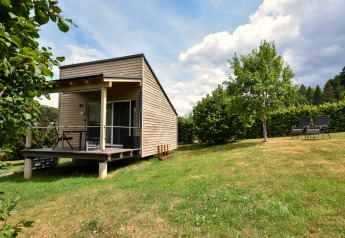 Mobilhjemmet Holiday home Terra 2 Persons med træterrasse, græsplæne og udsigt til natur og træer.