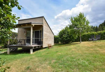 Mobil-home Holiday home Terra 2 Persons avec terrasse bois, pelouse, arbres et chaises de jardin extérieures.