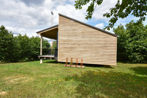 Casa mobile moderna 'Terra 2 Persons' in Germania con rivestimento in legno e veranda coperta in zona verde.