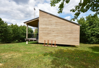 Mobil-home moderne « Terra 2 Persons » en Allemagne, revêtement bois et terrasse couverte dans un cadre vert.
