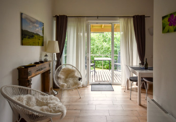 Lyst stueområde i mobilhome Terra for 2 personer med udsigt til balkon og grøn natur i Tyskland.