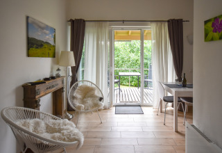 Lyst stueområde i mobilhome Terra for 2 personer med udsigt til balkon og grøn natur i Tyskland.