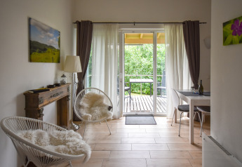 Bright living area in Terra mobile home for 2, featuring balcony view and lush greenery in Germany.