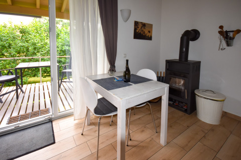 Lichte eetruimte in mobilhome met houtkachel en zicht op terras bij Holiday home Terra in Duitsland.