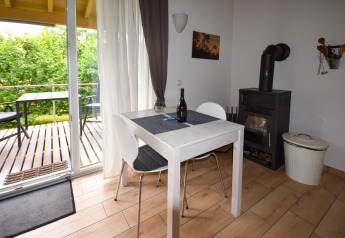 Coin repas lumineux avec table, poêle à bois et terrasse au Holiday home Terra en Allemagne.