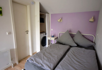 Soveværelse i mobilhome Holiday home Terra 2 Persons i Tyskland med dobbeltseng og lilla væg.