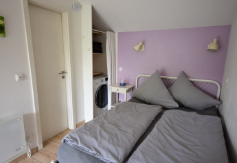 Chambre du mobil-home Holiday home Terra 2 Persons en Allemagne avec lit double et mur violet.