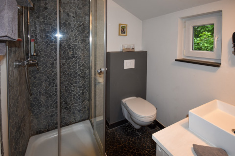 Bagno moderno in casa mobile con doccia, WC sospeso, finestra piccola e lavabo con asciugamano.