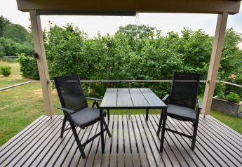 Outdoor terrace with two black chairs and table at Holiday home «Terra 2 Persons» in Germany.