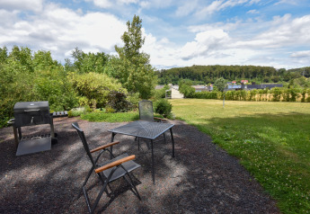 Garden area at Holiday Home Terra 2 Persons in Germany with grill, table, chairs and scenic landscape view.