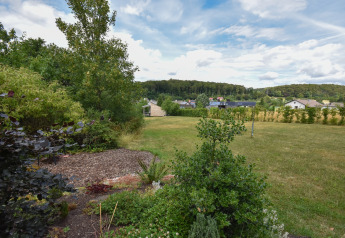 View of a spacious garden and lawn at Holiday home 'Terra 2 Persons' in Germany, with village in the background.