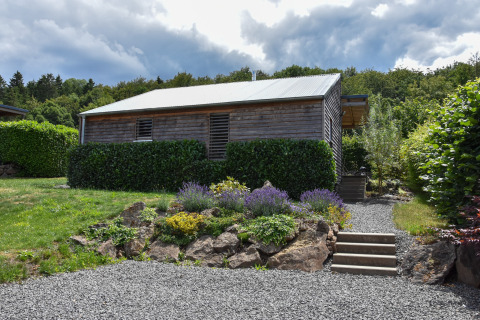 Casa vacanze Magma per 2 persone; cabina di legno con giardino, vialetto di ghiaia e vegetazione.