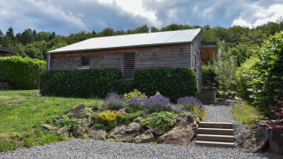Holiday home Magma for 2 persons; a wooden cabin with a garden, gravel path, and surrounded by greenery.