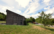 Maison de vacances ‘Magma 2 Persons’ en Allemagne avec façade en bois, pelouse, arbres et ciel bleu.