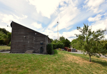 Maison de vacances ‘Magma 2 Persons’ en Allemagne avec façade en bois, pelouse, arbres et ciel bleu.