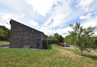 Casa de vacaciones ‘Magma 2 Persons’ en Alemania con fachada de madera, césped, árboles y cielo azul.