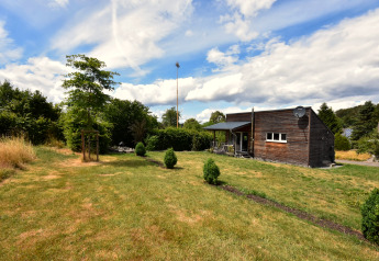 Vue sur la maison de vacances Magma 2 personnes en Allemagne avec cabane en bois et grand jardin vert.