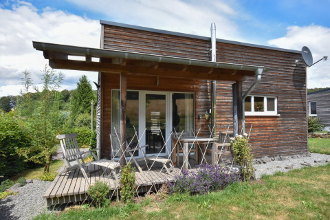 Casa vacanze in legno con patio e mobili da giardino a Holiday home «Magma 2 Persons» immersa nel verde in Germania.