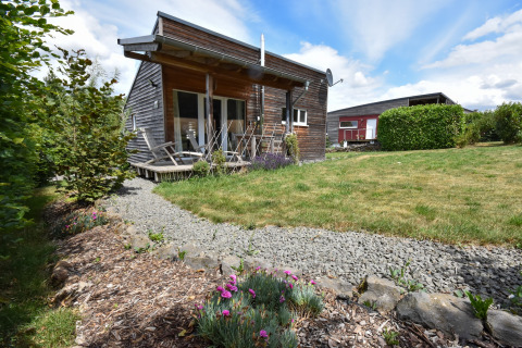 Vakantiehuis in hout met ligstoelen, grindpad en tuin onder blauwe lucht bij Magma 2 Persons in Duitsland.