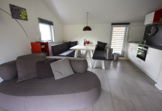 Modern living room and kitchen in Holiday home 'Magma 2 Persons' in Germany featuring a corner sofa.