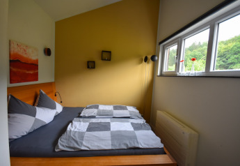 Moderne soveværelse med dobbeltseng, gule vægge og store vinduer i Holiday home Magma 2 Persons, Tyskland.