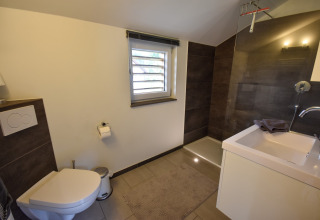 Moderne badeværelse med bruser, toilet og håndvask i ferieboligen Magma 2 Persons, Tyskland.