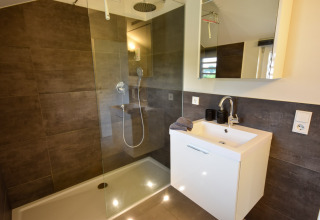 Bagno moderno nella casa vacanze Magma 2 Persons in Germania con doccia e lavabo bianco elegante.
