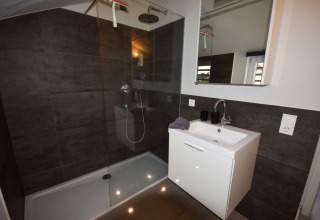 Moderne badkamer met inloopdouche, witte wastafel en spiegel in Holiday home Magma 2 Personen in Duitsland.