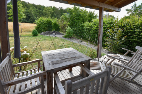 Wooden patio furniture on deck overlooking a garden, taken at Holiday home Magma 2 Persons in Germany.